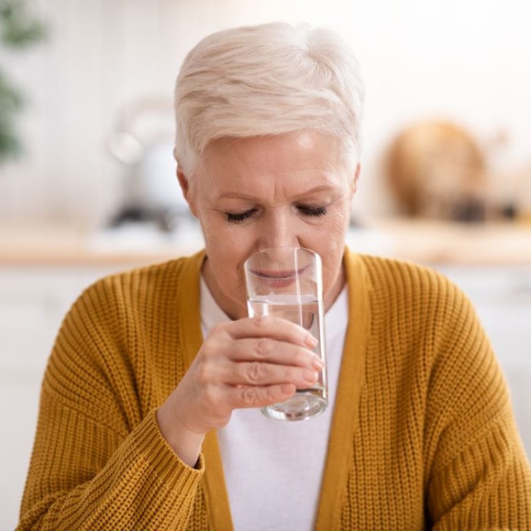 good-looking-senior-lady-drinking-still-water-at-h-YCV99CS