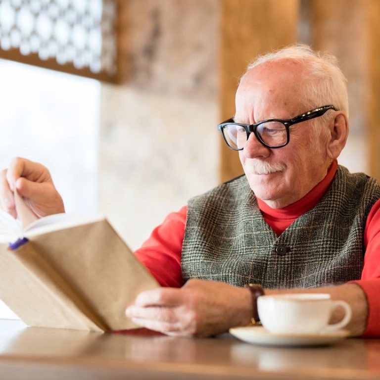 thoughtful-old-man-reading-book-in-cafe-S9QEZ5A
